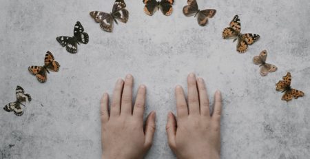 Zwei Kinderhände umgeben von Schmetterlingen